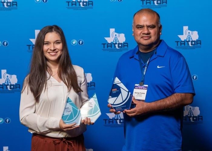 Two people holding three glass trophies