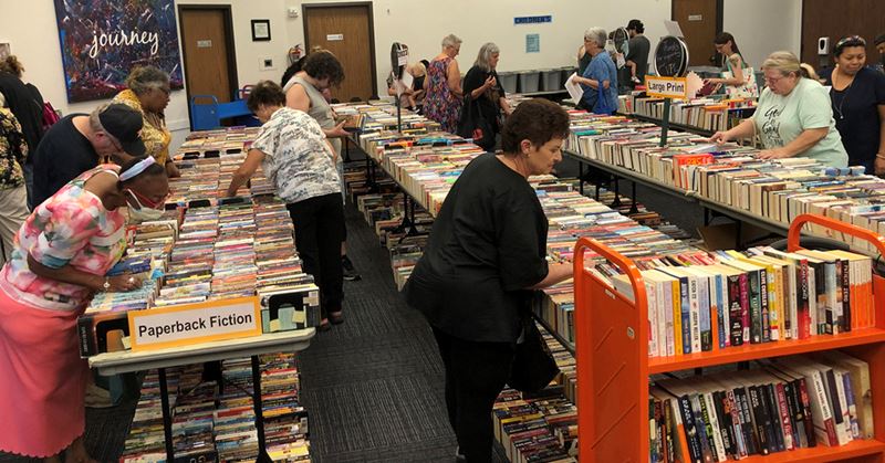 People browse collections of books set up on folding tables in the library's Bronte Room.