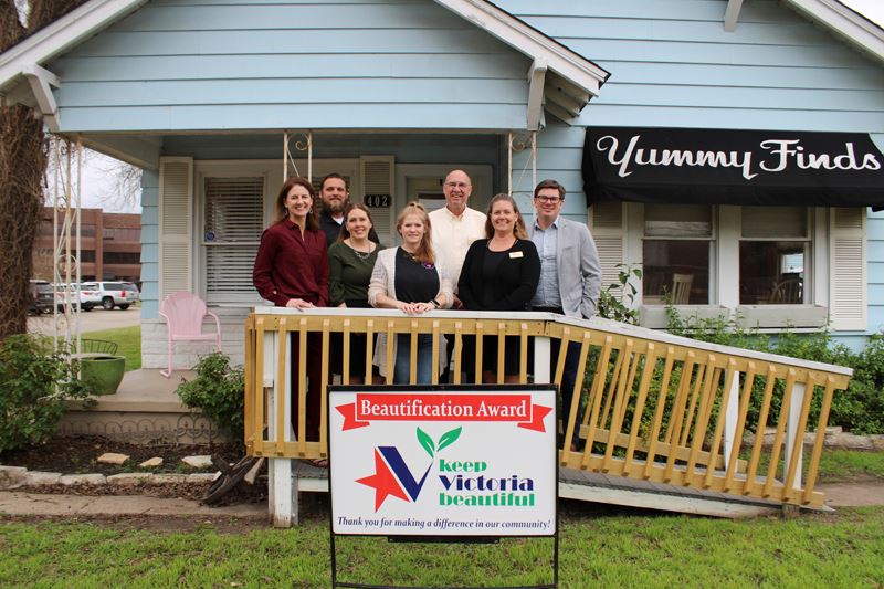 Group photo on ramp leading up to Yummy Finds, a blue cottage type building