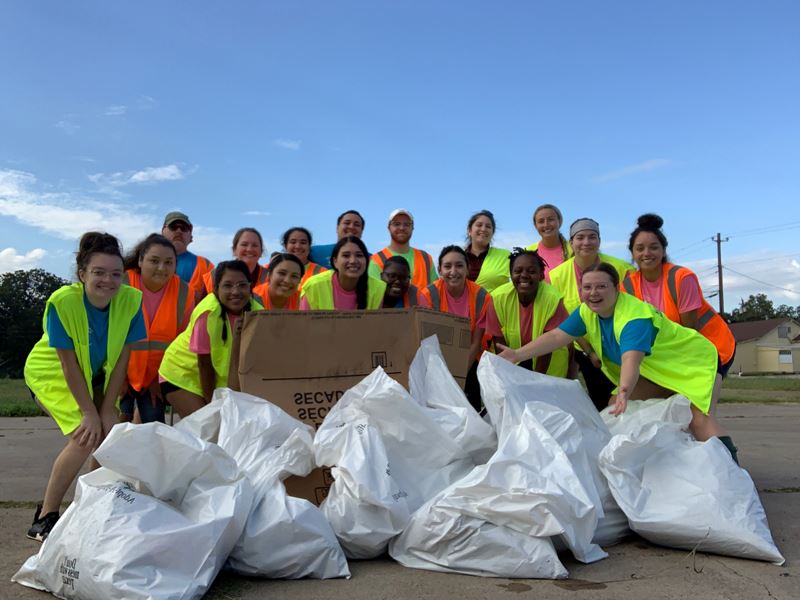 Group photo of people in safety vests next to bags of trash