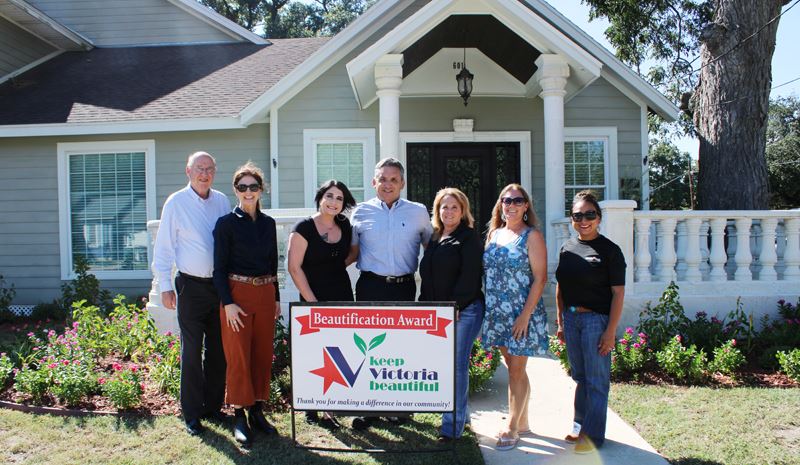 Group photo with KVB sign in front of house lined with flowerbeds