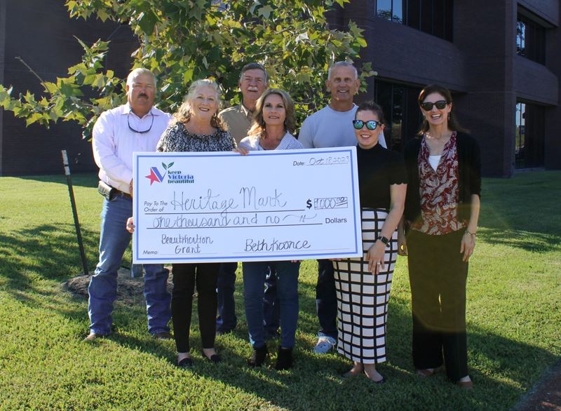 Group photo with giant check in front of young trees