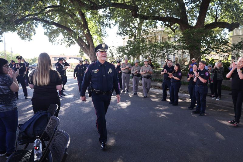 Deputy Chief Mark Jameson walks down Bridge Street lined by rows of applauding officers
