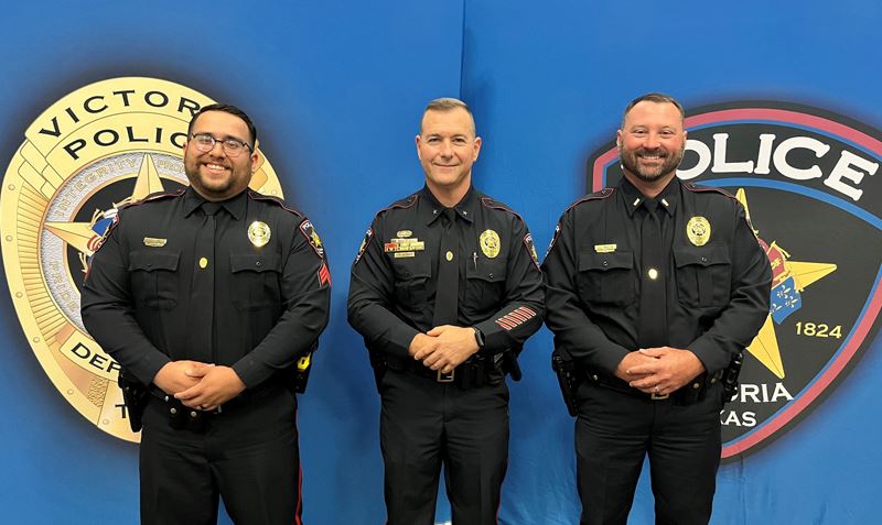 Three uniformed police officers pose for a photo