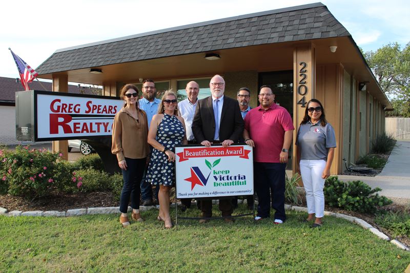 Group photo with KVB sign in front of Greg Spears Realty with flowerbeds