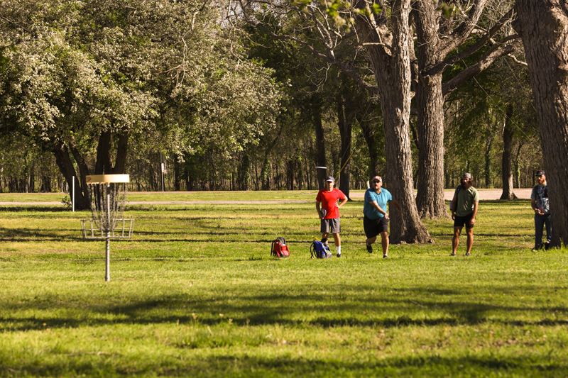 One man throwing a disc at the target while three other men watch 