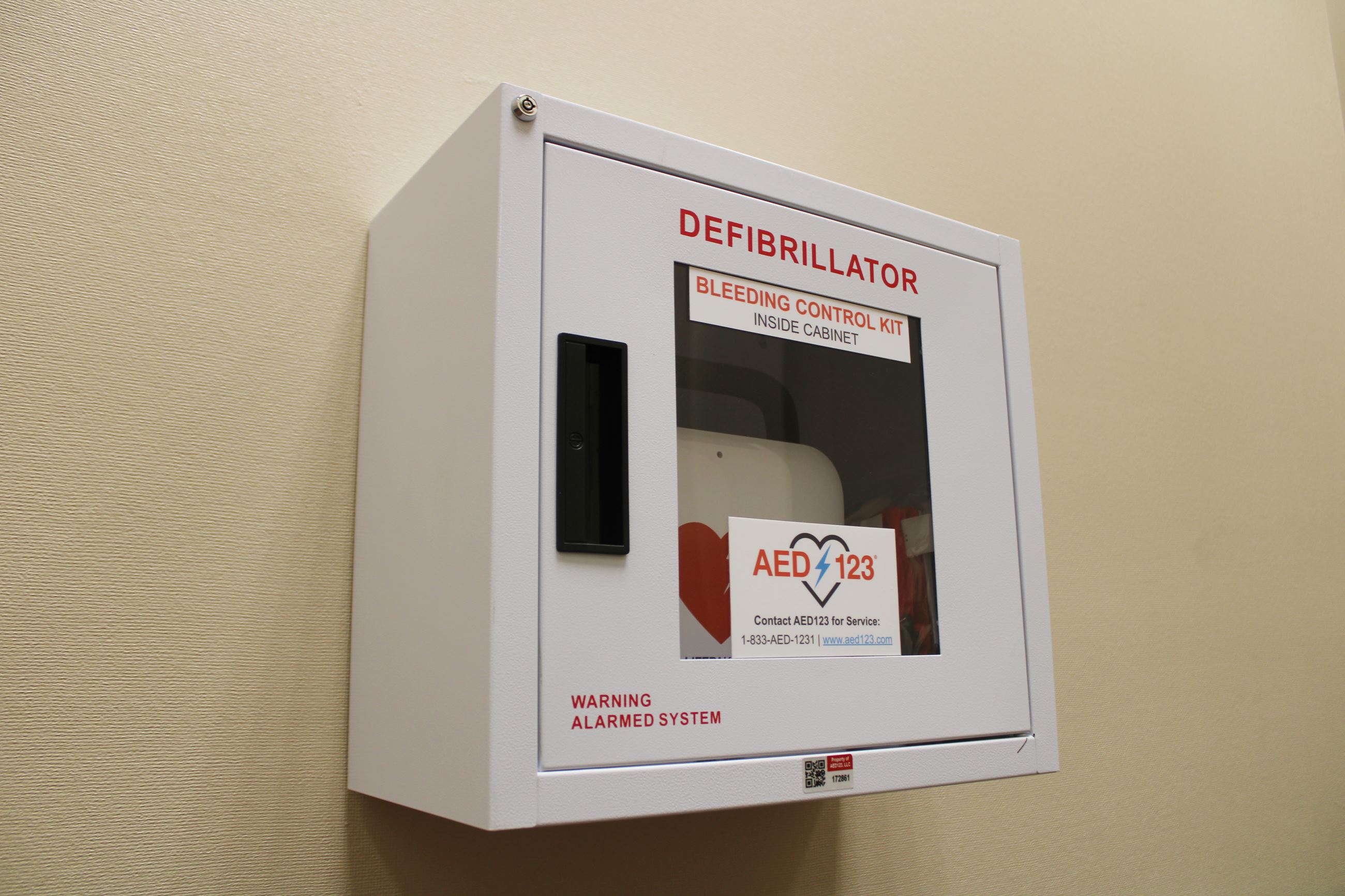 An AED in a box with a transparent door mounted on a wall