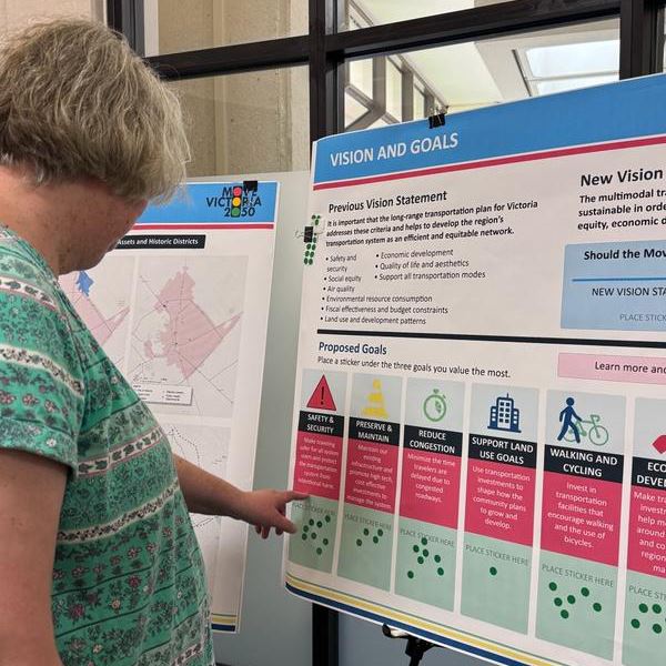 A woman looking at a poster board with icons and text related to transportation