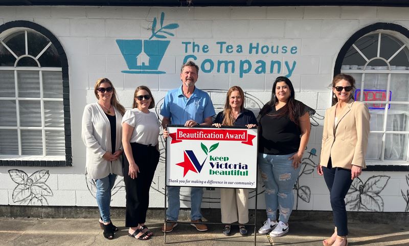 Group photo in front of a mural with flowers and the blue Tea House Company logo