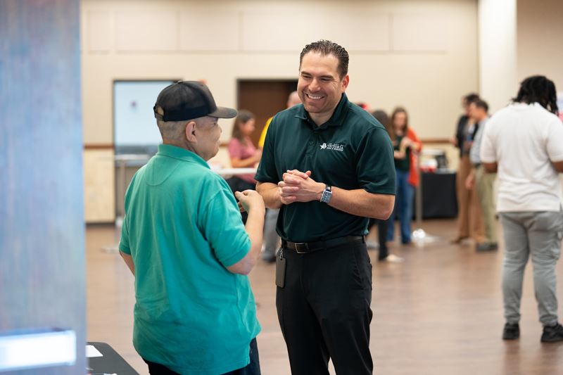 Two men smiling and talking in the Community Center annex