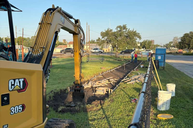 Excavator digging foundation for a sidewalk at Brownson Park