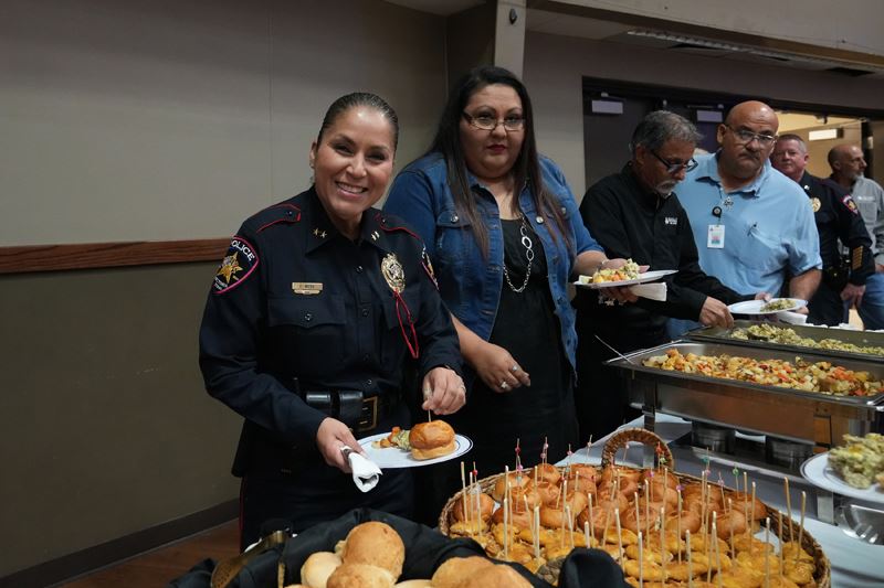 A line of people filling plates at a breakfast buffet, including uniformed police officers