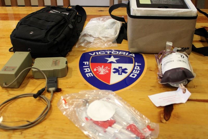 Equipment including an ice chest, a bag of frozen blood and medical tubes laid out on a table.