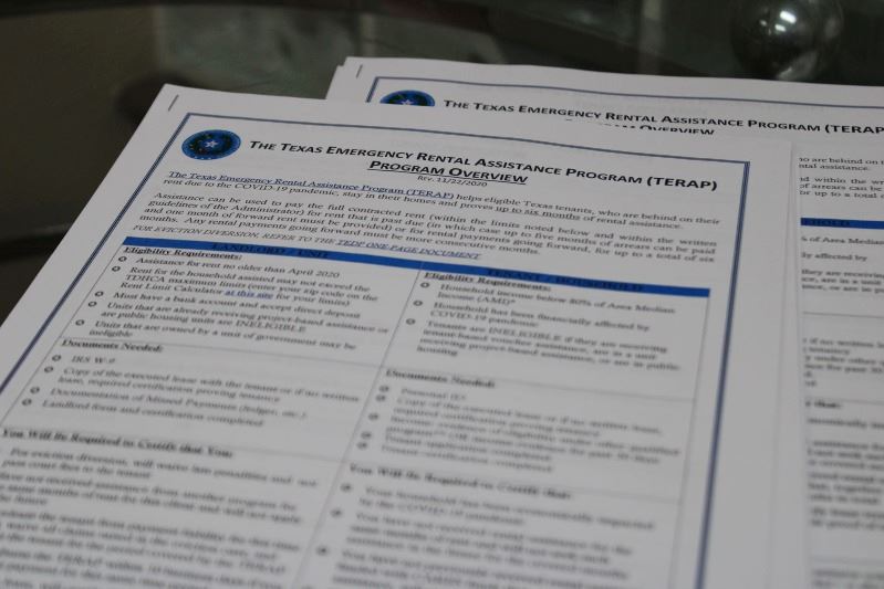 Application forms for the Texas Emergency Rental Assistance Program stacked on a glass side table.