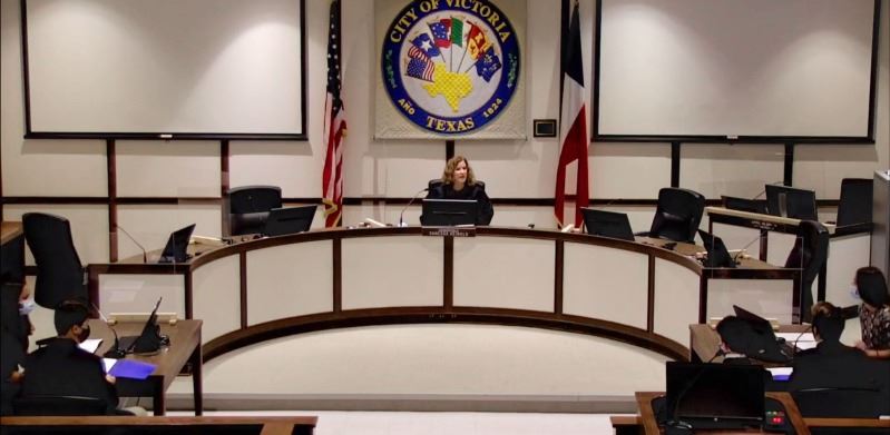 Judge at dais addresses middle school students in socially distanced setting