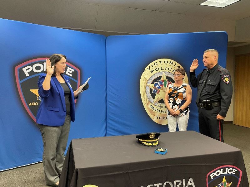 Man in police uniform raises his hand while being sworn in by the city secretary.