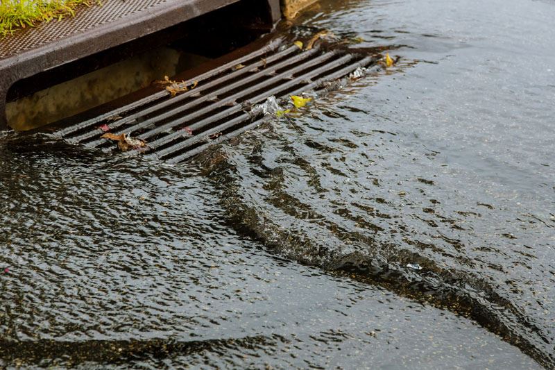 Water in a flooded street flows into a gutter