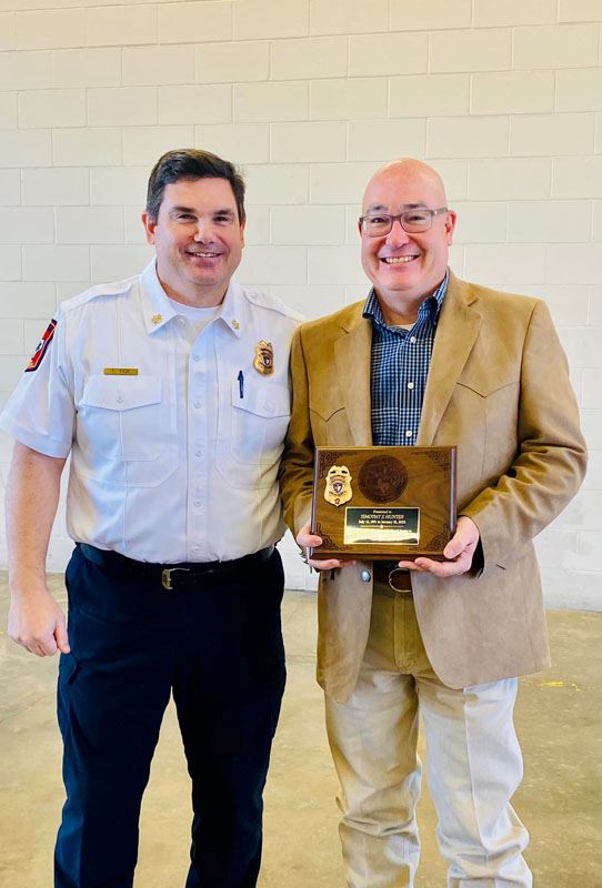 Two men pose for a photo with a plaque.