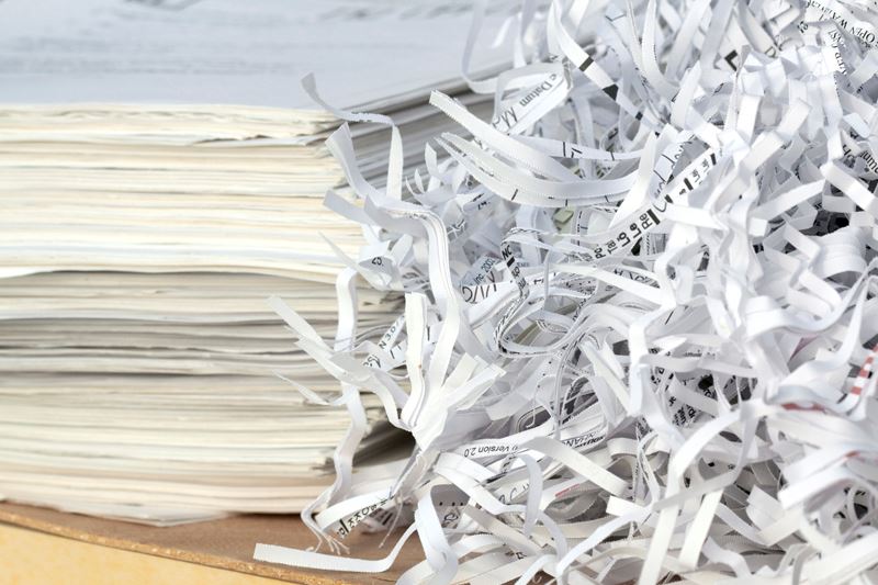 Stack of paper next to shredded papers