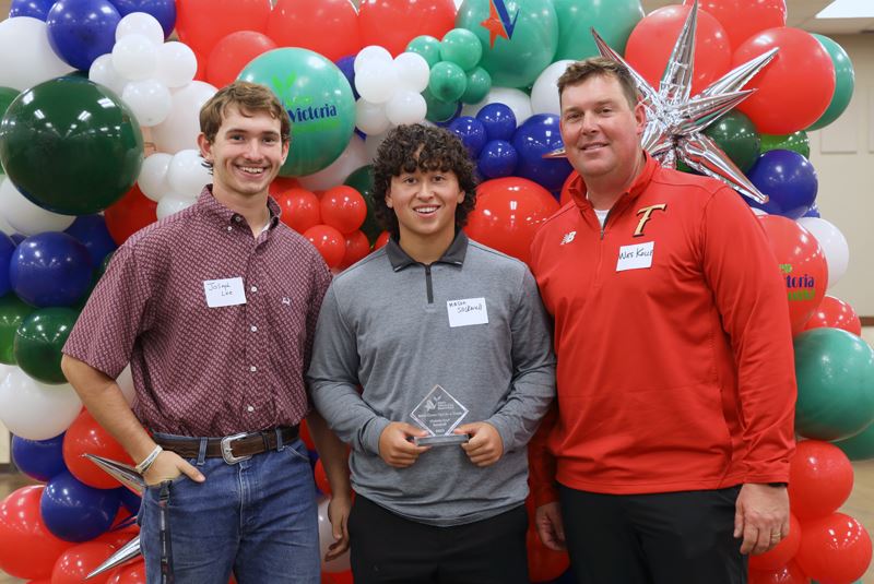 Three people in front of balloon backdrop with KVB logos on some balloons