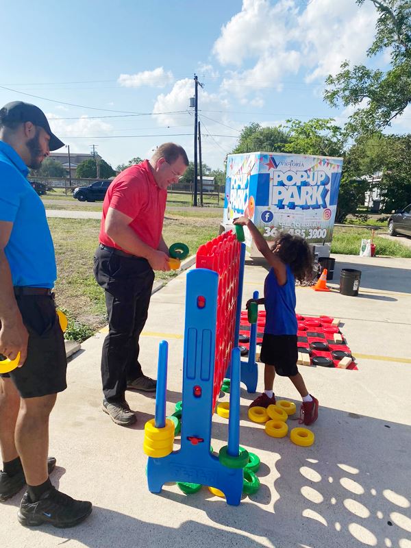 An adult and a child put giant Connect Four tokens in a giant Connect Four board