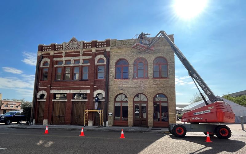 The downtown Greeks 205 building with a crane operating near the top and another worker at the door