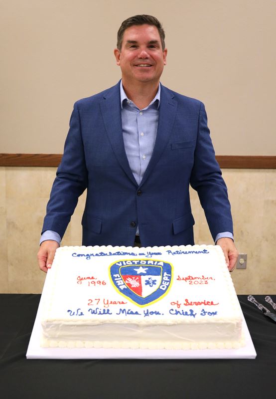 Chief Fox poses with a cake decorated with the fire department logo