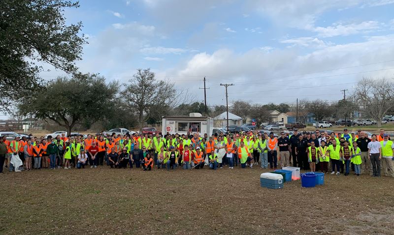 Large group of people in safety vests in a park in front of a Salvation Army food truck