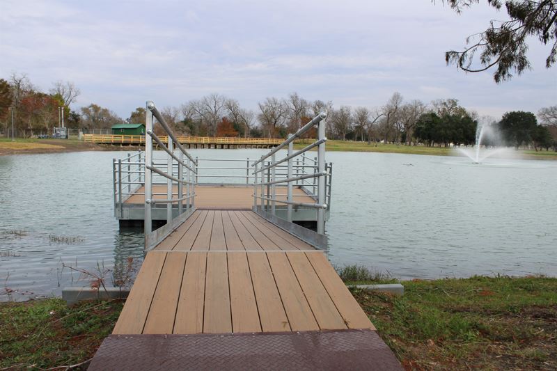 A fishing pier featuring a gentle slope down to a railed area