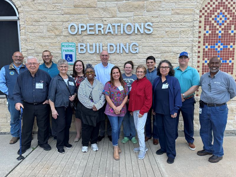 Group photo in front of a wall with a sign that says Operations Building