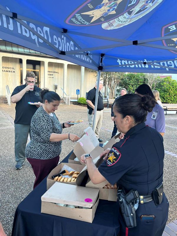 People getting pastries and coffee at a refreshment table in the City Hall courtyard