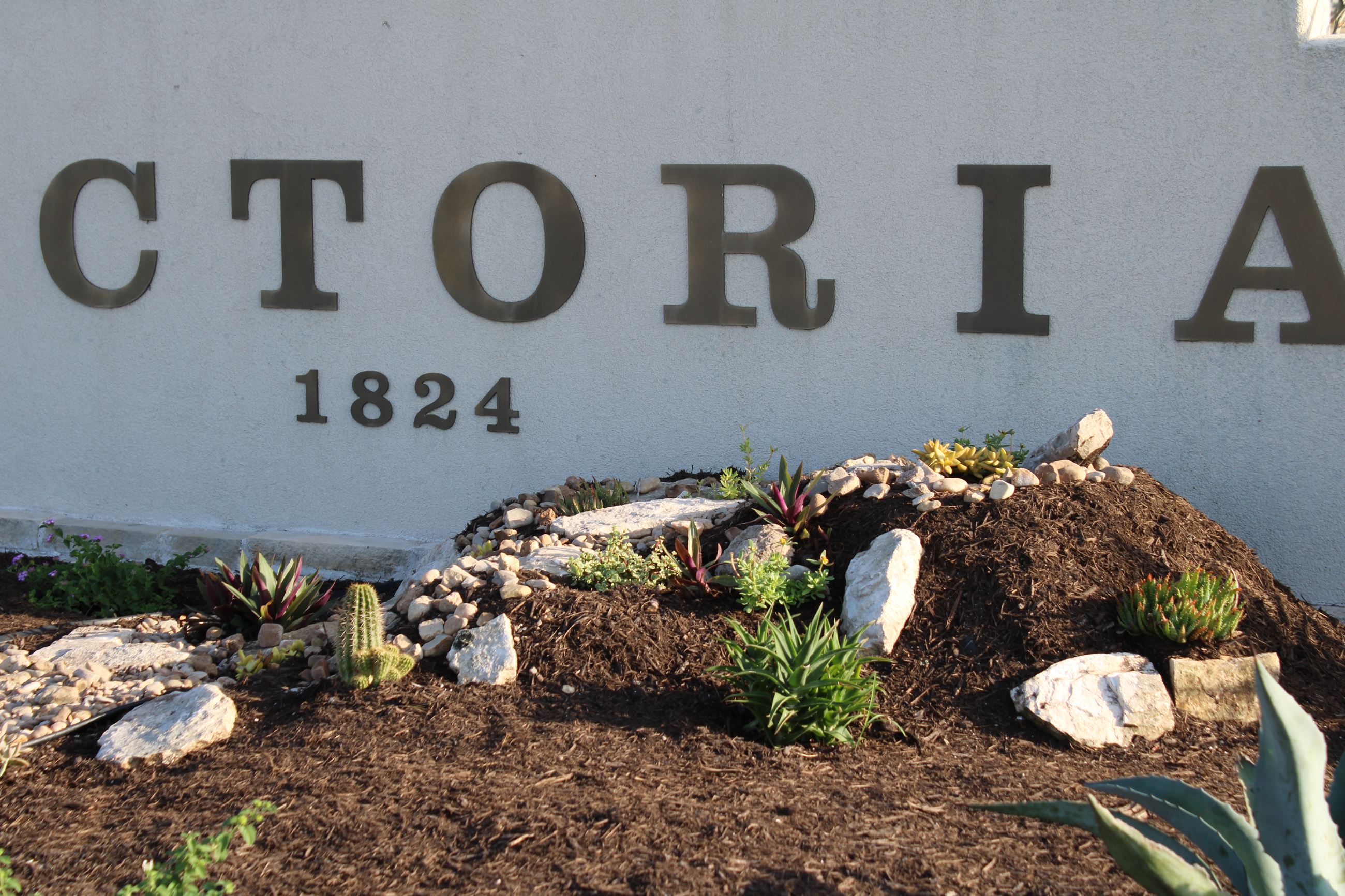 Stones and cacti in front of Welcome to Victoria sign