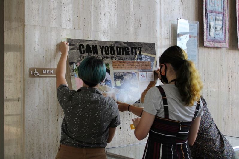 2 women adjusting sign
