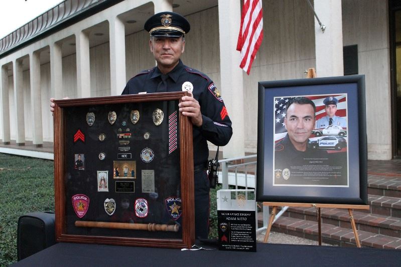 Sergeant Adam Nieto holds a shadow box at an outdoor retirement ceremony.