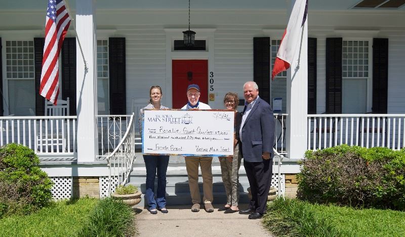 Four people pose with giant check at Rosalie Guest Quarters, a bed and breakfast downtown