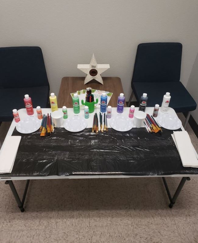A table lined with craft paints and paintbrushes