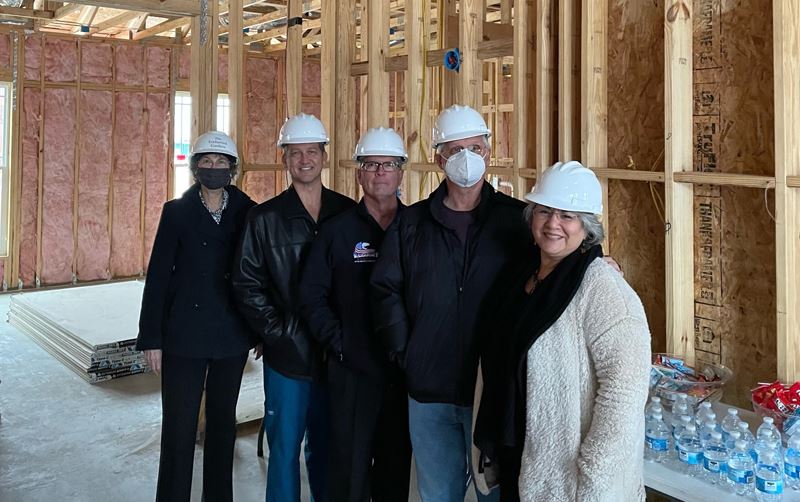 City Council members wearing hard hats pose for a photo in an unfinished building