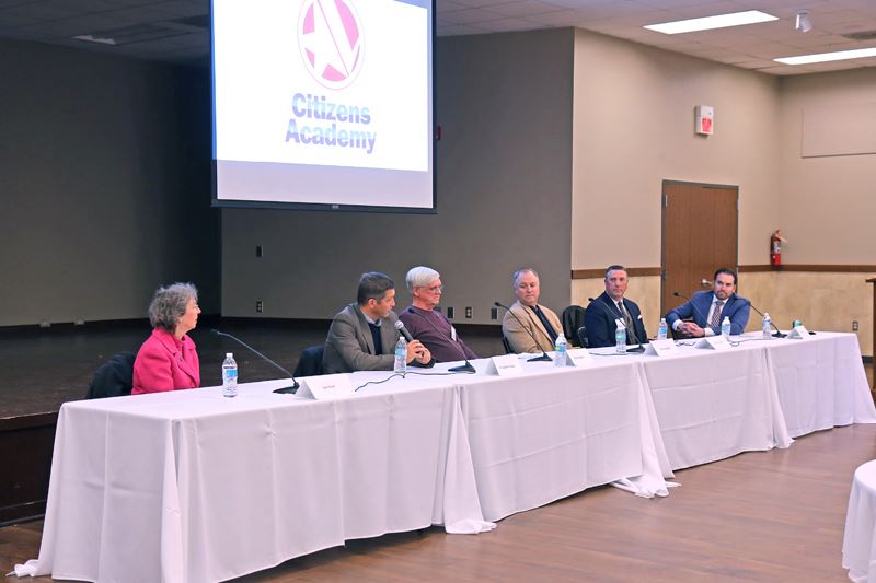 Row of people seated at a table with microphones