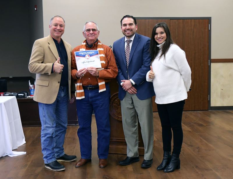 Group photo of four people. One holds a certificate with a Citizens Academy logo.