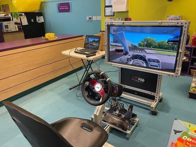 A chair in front of a monitor with a driving game set up.